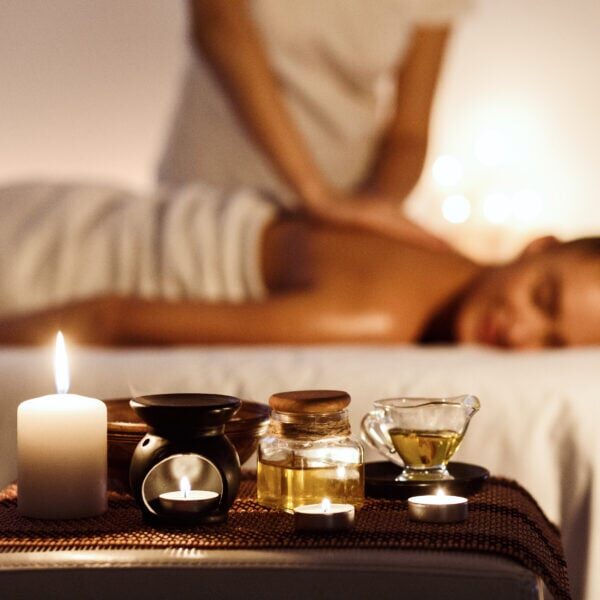 Aroma spa. Woman enjoying massage in luxury spa with candle on foreground